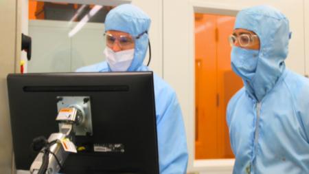 Researchers in cleanroom suits working with equipment in the Scottish Microelectronics Centre